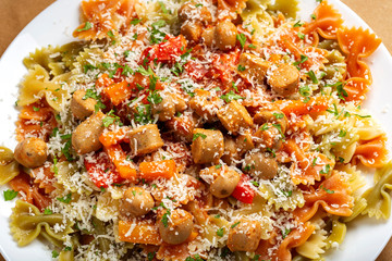 Farfalle pasta with sausages, vegetables and grated parmesan