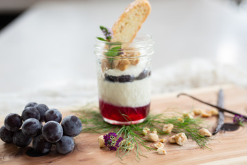 Vanilla Panna Cotta with a Concord Grape Gelee Topped with Whipped Chantilly Cream and Toasted Hazelnut and Served with a Slice of Hazelnut Biscotti