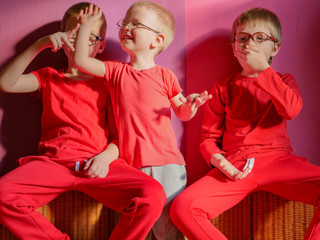 Funny children in red clothes posing in front of camera. Boys actively express their emotions. Preschoolers are happy together at home on vacation