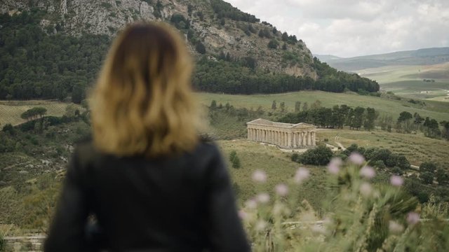 Woman standing with view of ancient ruins temple of Segesta in Sicily