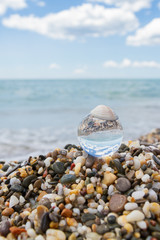 Fototapeta na wymiar Glass round ball on the beach reflects the sea in summer