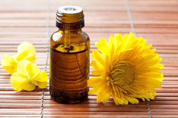 Bottle of essential oil and flowers on a bamboo background