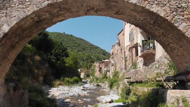 A drone flies over the small river of the medieval village of Zuccarello in Liguria, Italy
