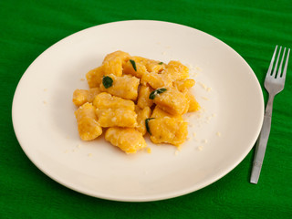 Pumpkin gnocchi with sage and butter on a white plate