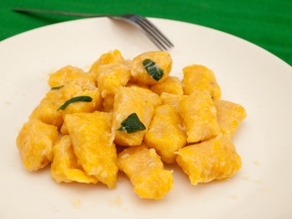 Pumpkin gnocchi with sage and butter on a white plate