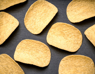 Stock of potato chips on black background. Many potato chips on black background