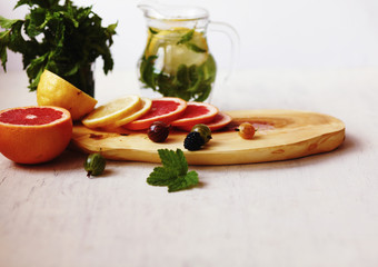 lemonade in pitcher, sliced lemon and grapefruit ,fresh berries and a bundle of fresh mint on a...