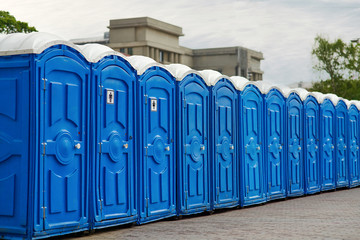 Long row of portable bio toilet cabins in a city street. Line of chemical toilets for the holiday,...