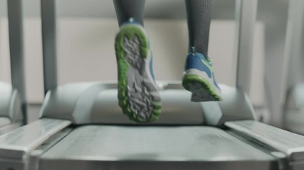 Closeup athletic feet running on running machine in fitness gym.