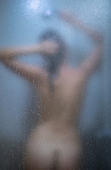 Woman taking a long hot shower washing her hair in a modern design bathroom