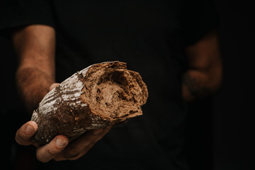 Male hands breaking freshly baked bread, closeup