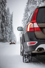 Car on a snowy winter road amid forests - using its four wheel drive capacities to get through the snow