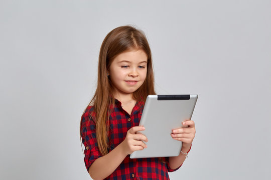 Teenage girl with emotional facial expression. Beautiful female half-length portrait on light background. Teenager with a tablet in his hands