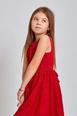Teenage girl with emotional facial expression. Beautiful female half-length portrait on light background. Teen girl in a beautiful red dress