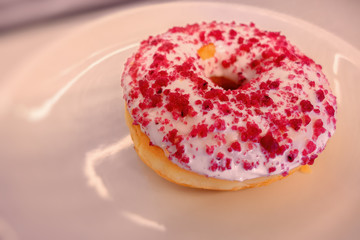 A delicious strawberry donut on a plate