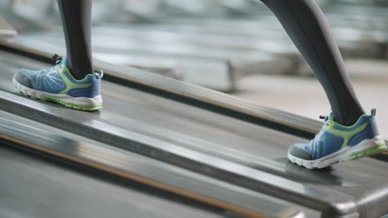 Closeup two pair of feet moving on treadmill in fitness gym.