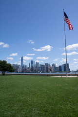 Portrait view on skyline of Lower Manhattan in New York from Ellis Island with an American Flag