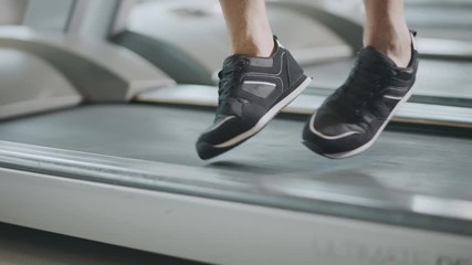Closeup feet moving on treadmill in fitness gym.