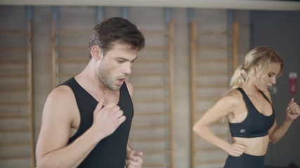 Tired trainers finishing cardio exercise on run machine in fitness center.