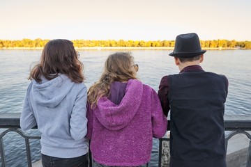 View from the back of three teenager friends boy and two girls