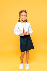 Fototapeta premium happy schoolkid holding color pencils on orange