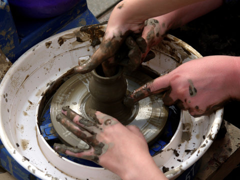photo of hands on the Potter's wheel, giving the shape of clay