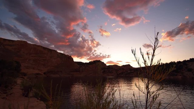 View of sunset at Red Fleet Reservoir in Utah moving past bush in slow motion.