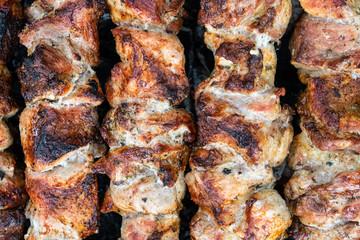 Frying pork on a skewer over a brazier. Turning meat over coals. Appetizing shish kebab.