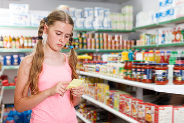 Serious girl using list  for check product