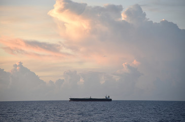 Obraz premium Ocean sunset with cargo ship sailing to the port of her destination. 