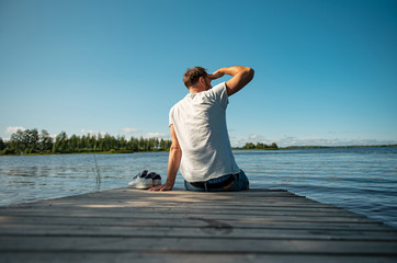 Mann sitzt auf Holzsteg am See in Finnland - 285354769