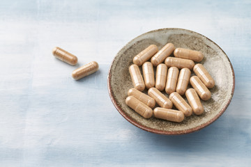 Kudzu Root capsules. Concept for a healthy dietary supplementation. Bright wooden background. Close up. Copy space