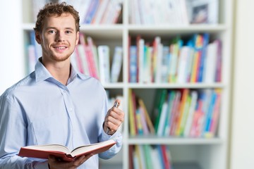 Young male teacher   standing with book