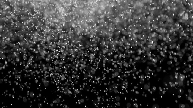 White Particles in the Fall. Small white particles flow in the air on a black background to simulate snow, blizzard, or a microcosm of the Christmas magic. Filmed at a speed of 120fps