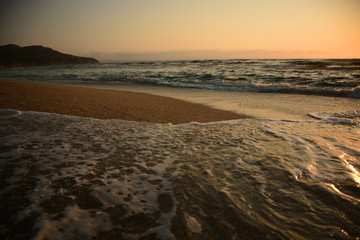 Dramatic scene at sunset of the waves breaking on the shoreline