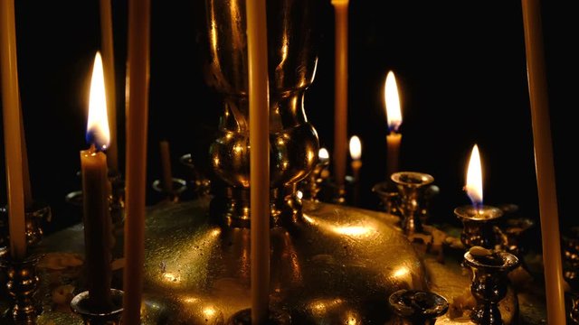 Subtle church candles burn in an Orthodox Christian church near holy images in the dark in high resolution 4k