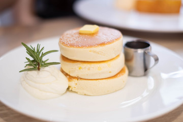 Honey pancakes and butter on the white dish.