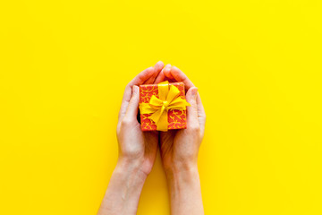 box for gifts in hands on yellow background top view mock up