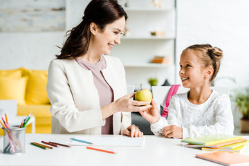 Obraz premium happy mother giving tasty apple to cute daughter