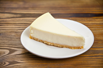 classic cheesecake on white plate on  wooden table