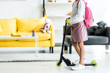 cropped view of kid standing near kick scooter at home