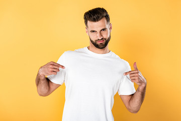 egotistical handsome man in white t-shirt pointing with fingers at himself isolated on yellow - obrazy, fototapety, plakaty
