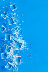 Pile of ice cubes on blue bar desk background top view mock up