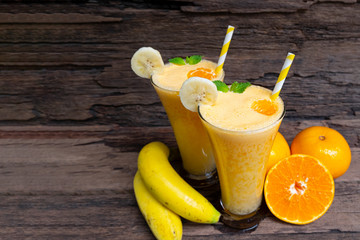 Banana and orange smoothies yellow colorful fruit juice milkshake blend beverage healthy high protein the taste yummy In glass drink to lose weight drink episode on wooden background. 