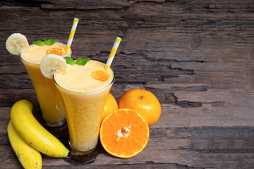 Banana and orange smoothies yellow colorful fruit juice milkshake blend beverage healthy high protein the taste yummy In glass drink to lose weight drink episode on wooden background. 