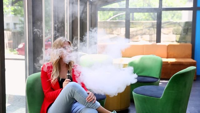 Stylish girl in a city. Lady use the electronic cigarette