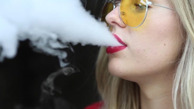 Stylish girl in a city. Lady use the electronic cigarette