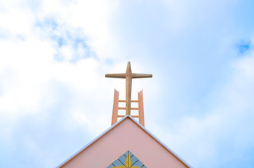 Cross on a church roof, white clouds and blue sky in bacground.