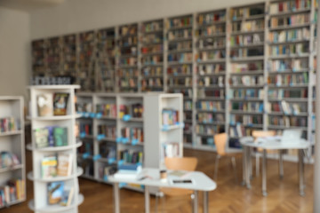 Blurred view of bookshelves and tables in library