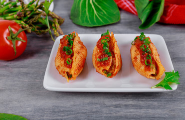 Pasta shells stuffed with minced beef meat and tomato sauce on a plate.